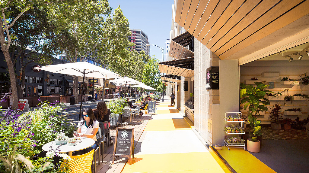 A group of people sitting at tables outside a building.