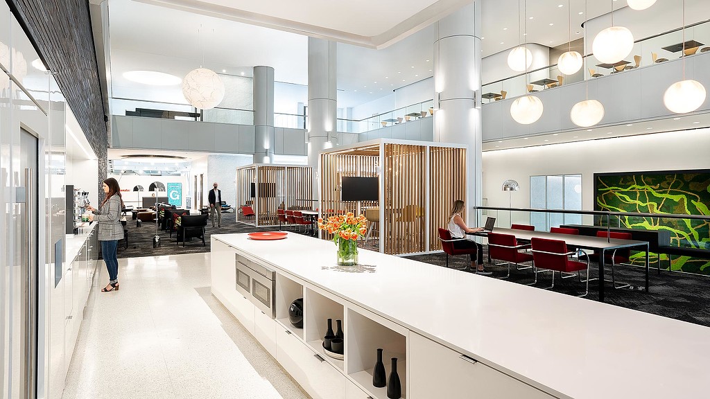 A long white counter with a couple of people sitting at it.