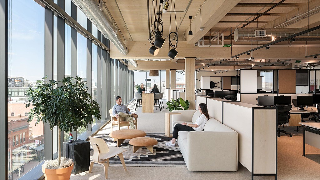 A man and woman sitting in a room with a large window.