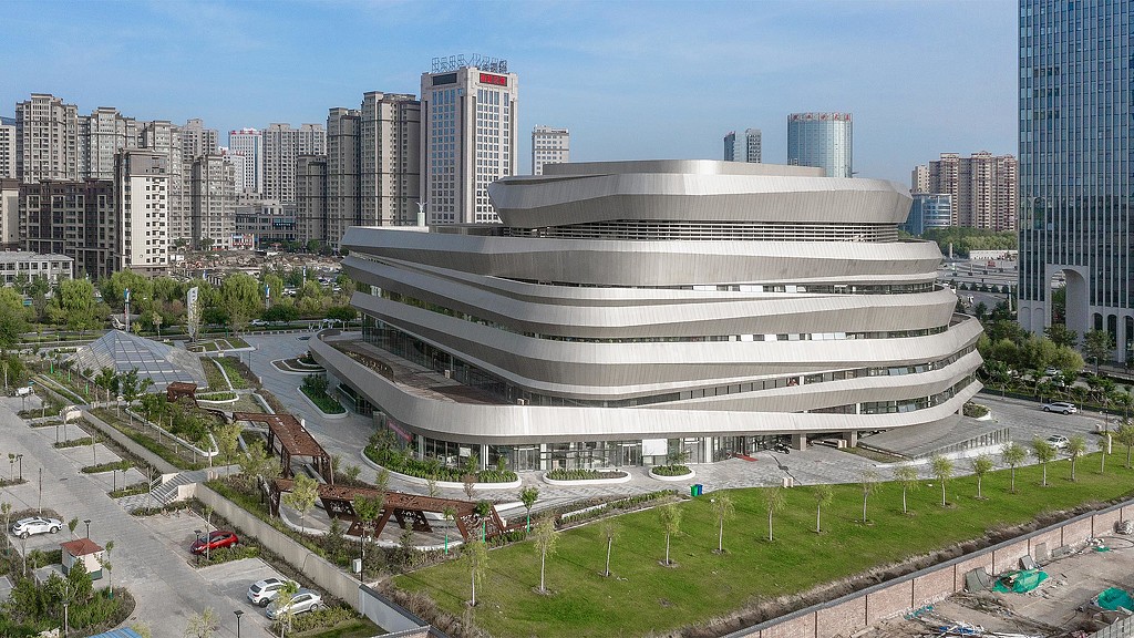 A large stadium with a road and cars in front of it.