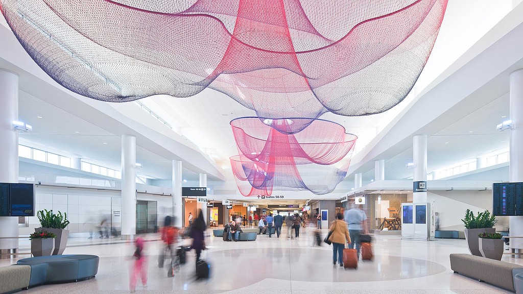 A group of people in a large building with a large pink and white ceiling.