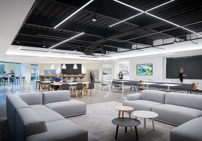 A room with a large screen and chairs and people in it.