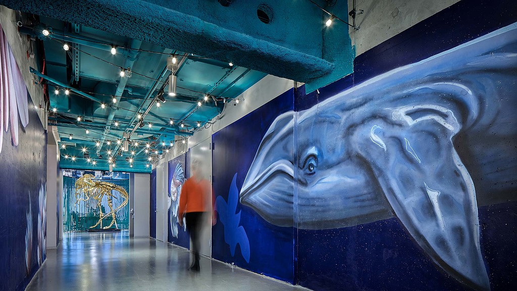 A person standing next to a large blue fish in a room.