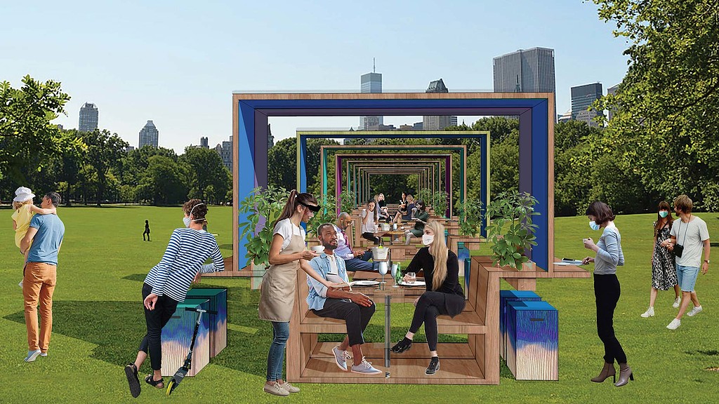 A group of people standing around a table outside.