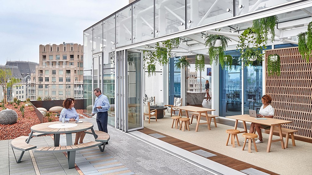 A group of people sitting at tables outside a building.