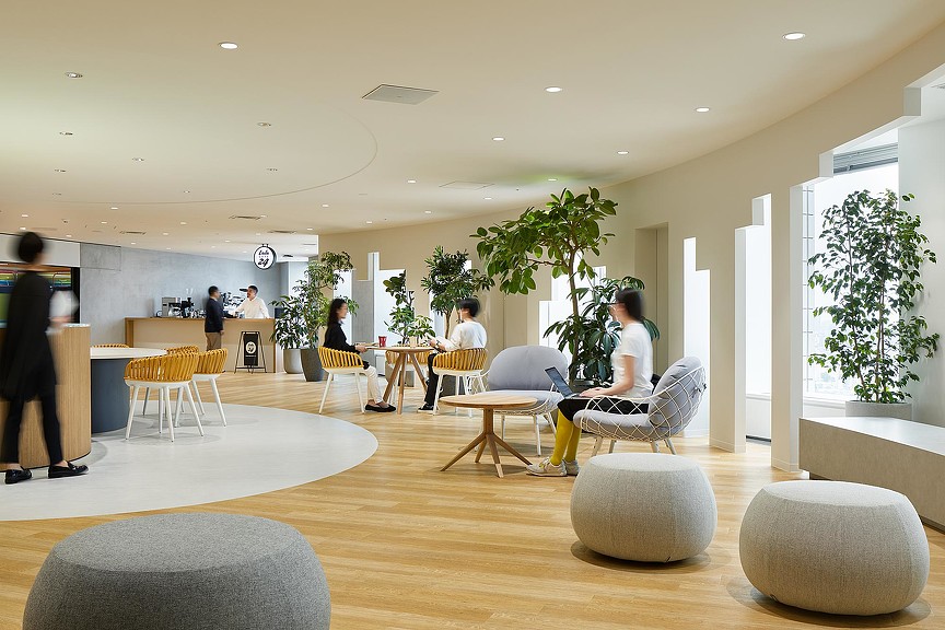 A group of people sitting in a room with a large plant.