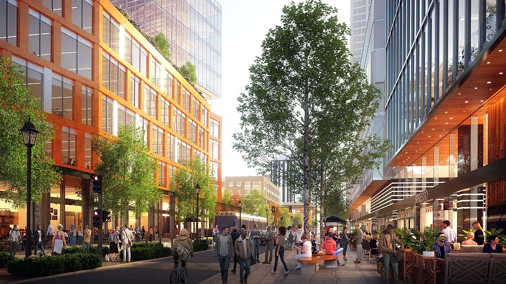 A group of people walking on a street between buildings.