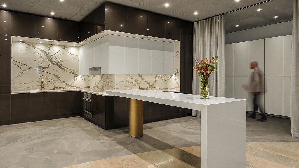 A person standing next to a large glass table with flowers on it.