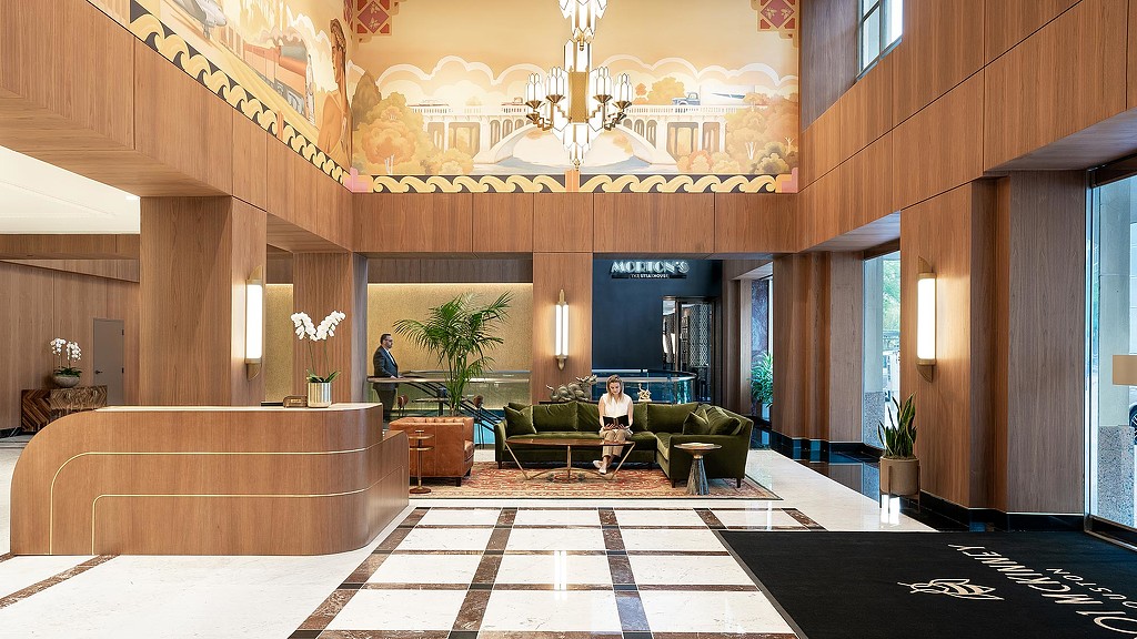 A room with a large chandelier and a couple of people.