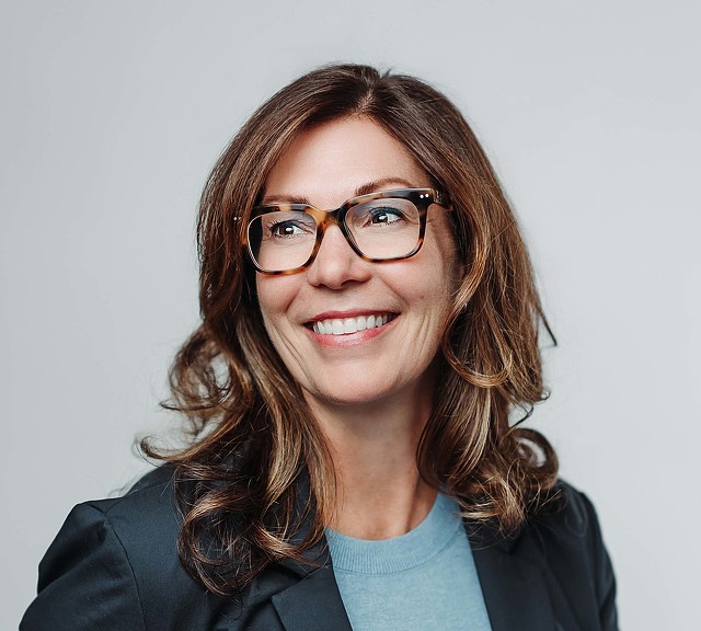 A woman with long hair and glasses.