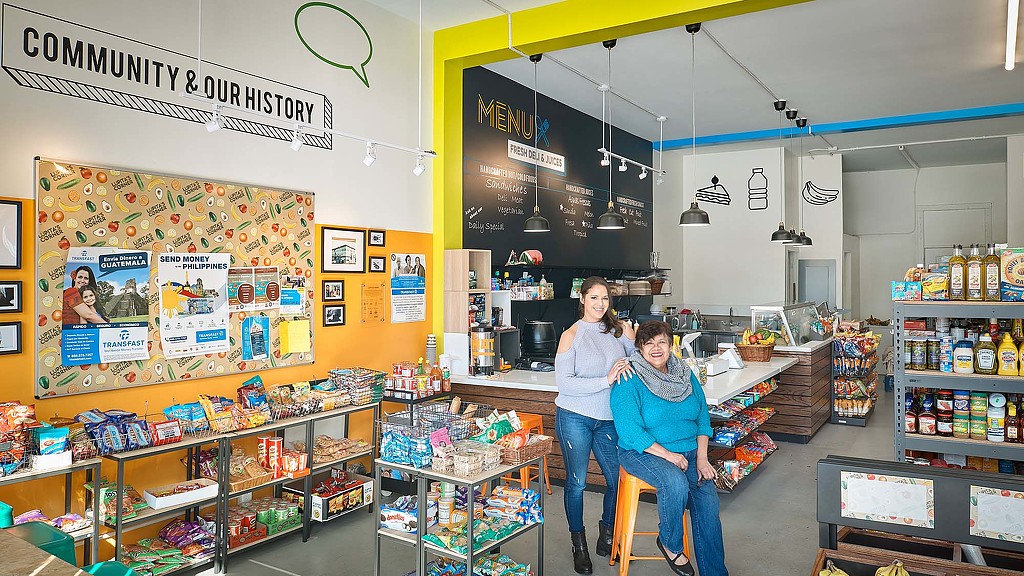 A couple of women sitting at a counter in a store.
