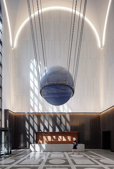 A person standing in a room with a large sculpture.