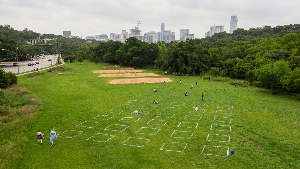 A group of people on a grassy field with a city in the background.