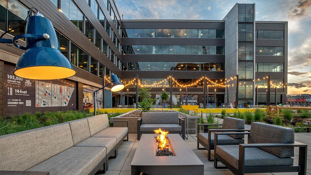 A fire pit in front of a building with a large glass front.