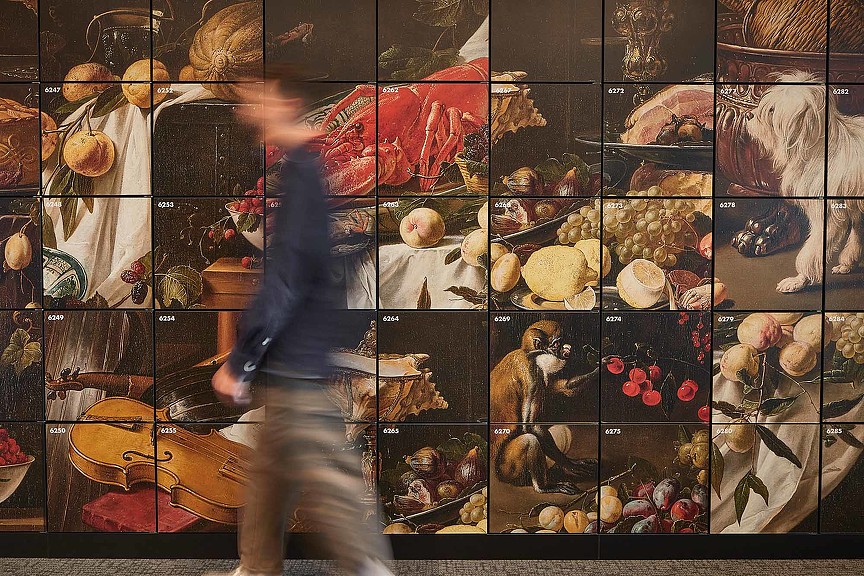 A person walking past a wall of pictures of cats.