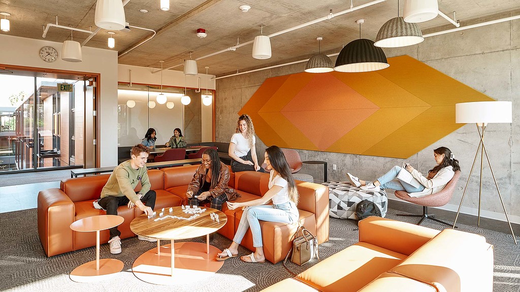 People sitting on couches in a room with a large screen.