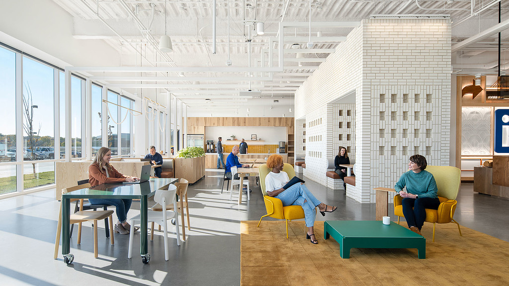 A group of people sitting in a room with tables and chairs.