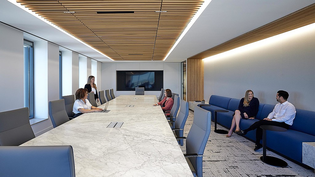 A group of people sitting in a room with blue couches.