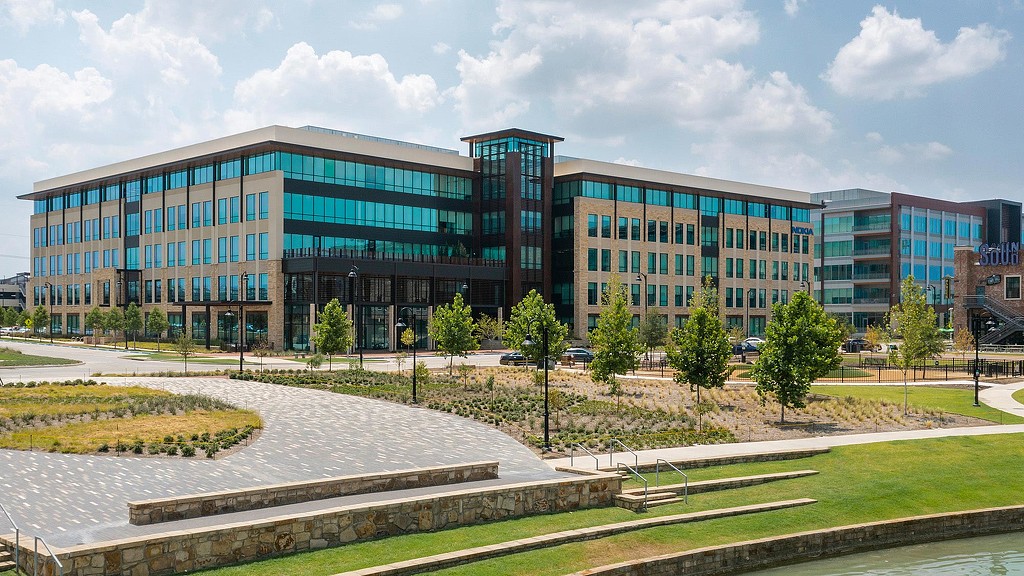 A large building with trees and grass in front of it.