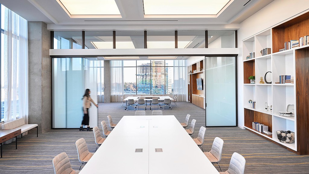 A person standing in a room with a large table and chairs.