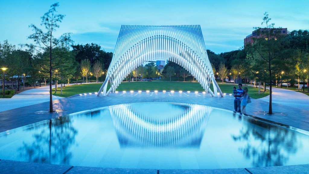A large glass building with a fountain in front of it.