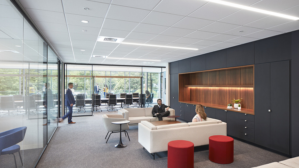 A man and woman sitting on a couch in a room with glass walls.