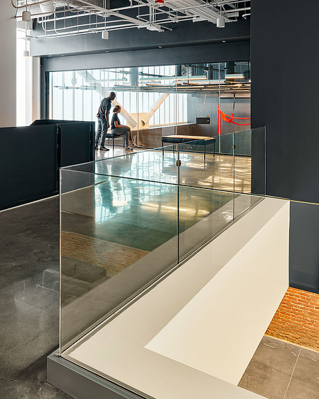 A glass walled room with a couple of people sitting at a table.