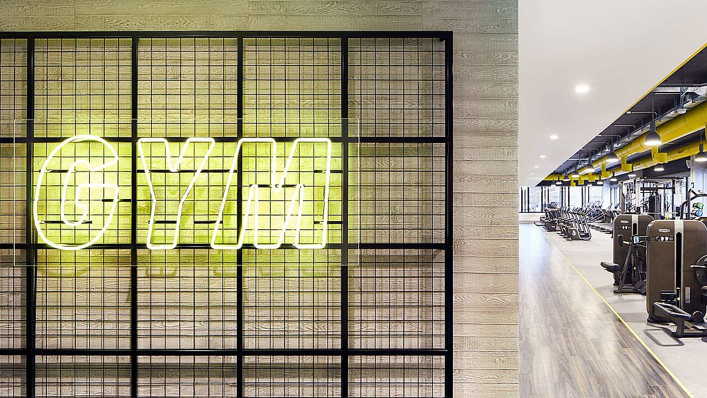 GYM neon yellow sign with gym equipment in background