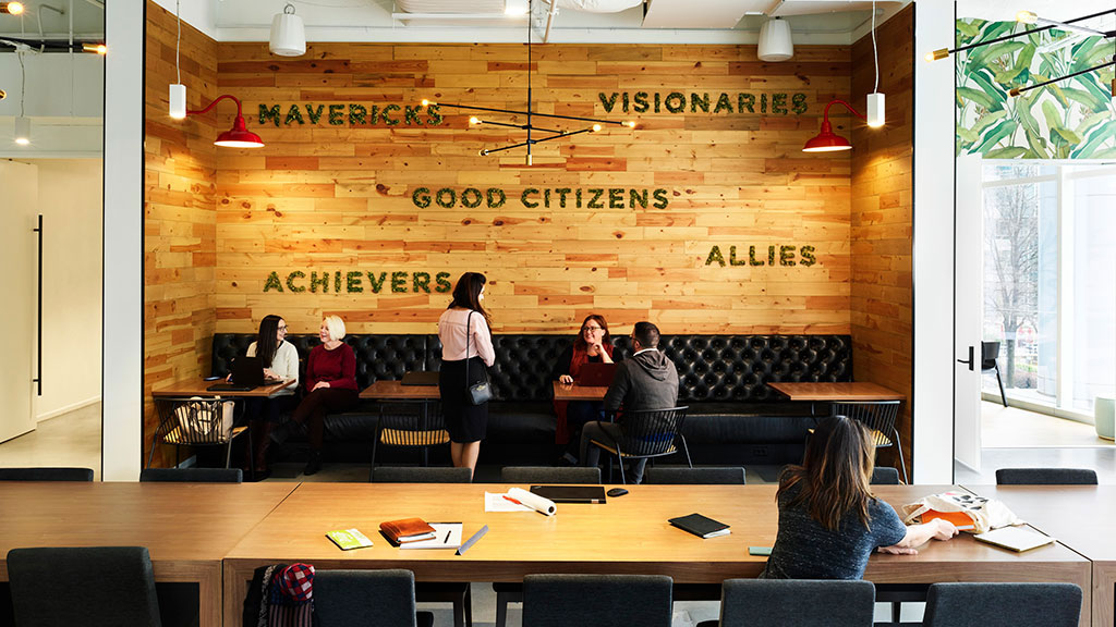 A group of people sitting in a room with a large wood wall.