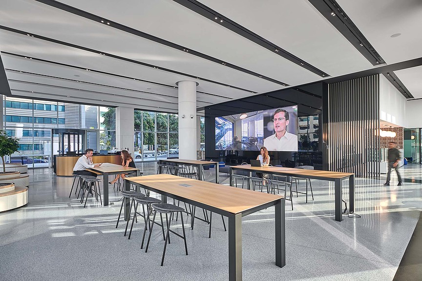 A room with tables and chairs and a large screen.