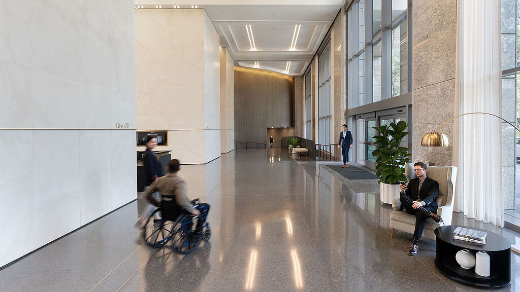 A person on a wheelchair in a large building with people walking around.