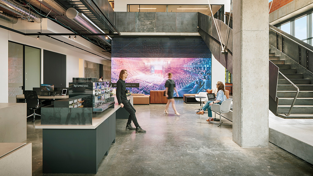 People in a room with a large screen.