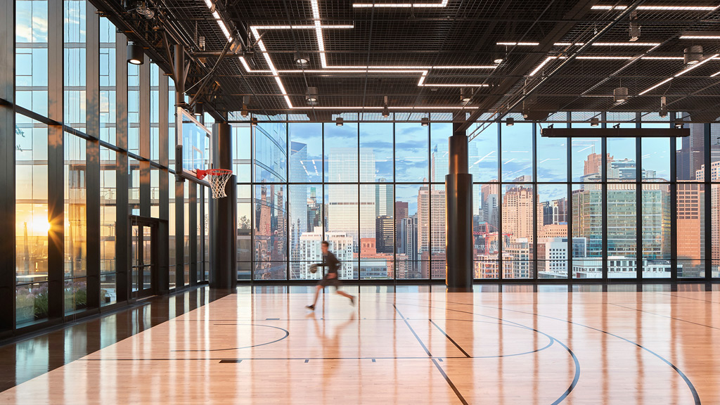 A person playing basketball in a large room with large windows.