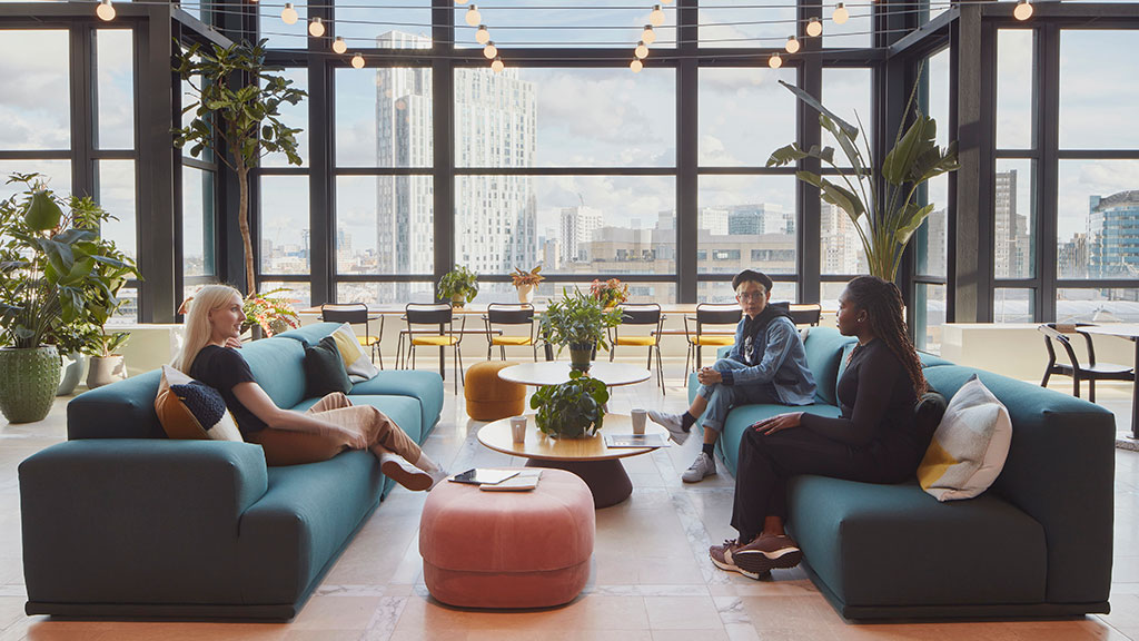 A group of people sitting on couches in a room with large windows.