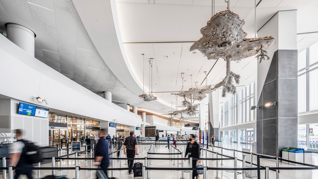 A group of people walking with luggage through an airport ticketing terminal.