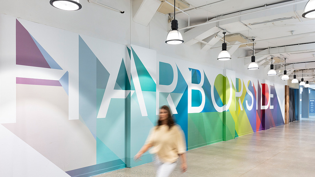 A woman walking through hallway with Harborside wall graphic.