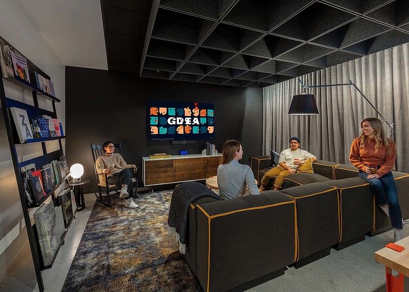 A group of people sitting on a couch watching a television.