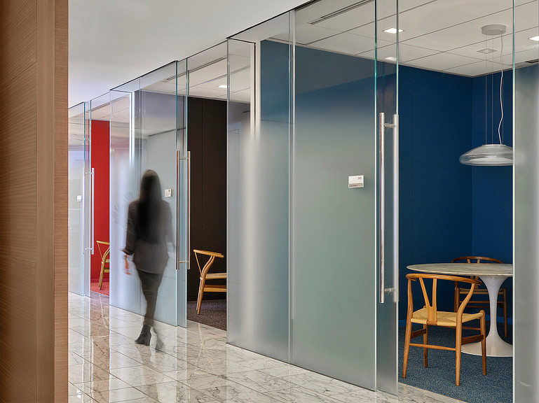 Person walking in hallway lined with small meeting rooms