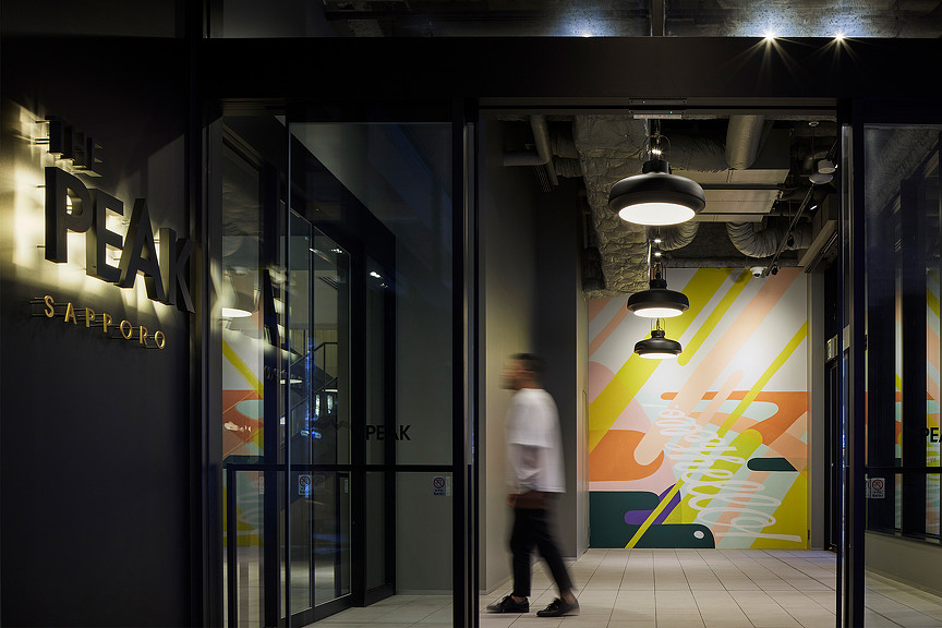 A man walking into The Peak Sapporo office building