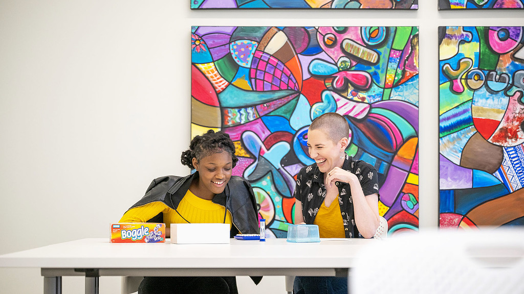 A man and woman sitting at a table with a map behind them.