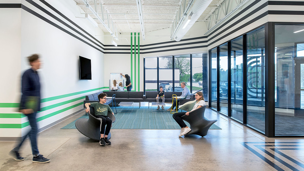 A group of people sitting in a room with windows.