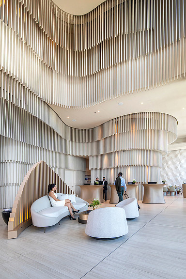 A person sitting on a couch in a large room with a large ceiling.