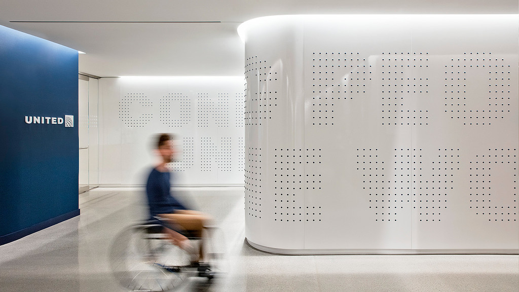 A bright modern hallway with united branding and a person in a wheelchair