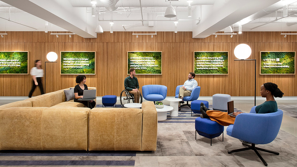 A large seating area with a comfortable sofa and a wooden accent wall at United Airlines lounge