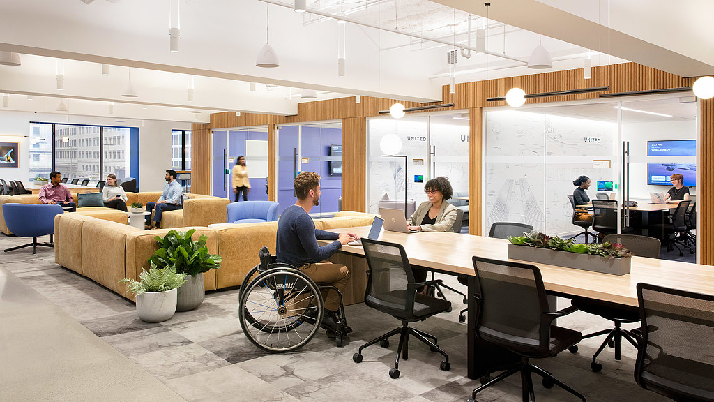 Seating nooks and long conference tables for wheelchair accessibility at United Airlines lounge
