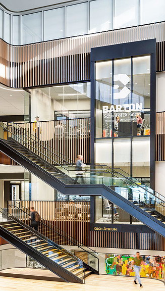People walking up stairs across multiple floors with Barton School of Business signage