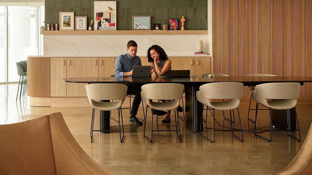 A man and a woman sitting at a table with a laptop.