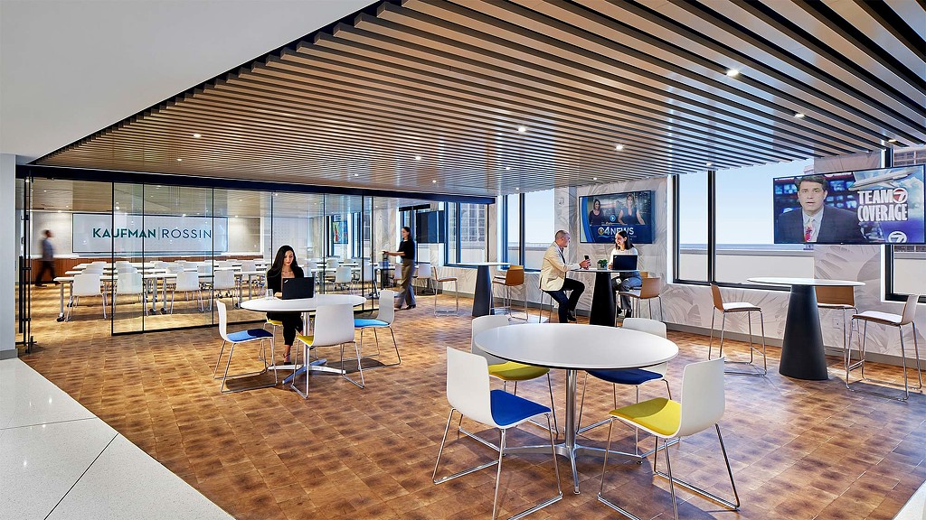 A group of people in a room with tables and chairs.