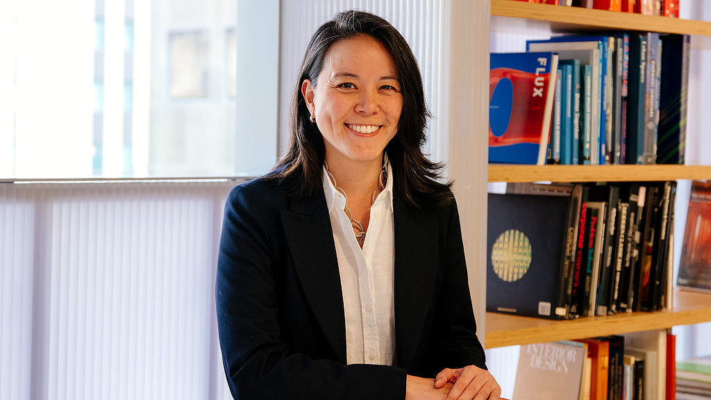 A woman smiling in front of a bookshelf.