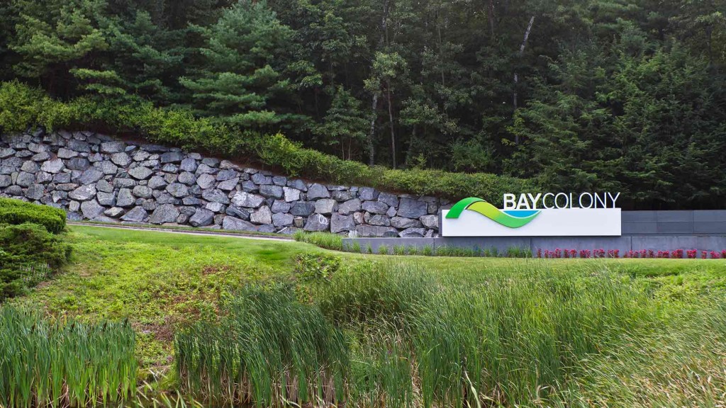 A stone wall with a sign on it and grass around it.